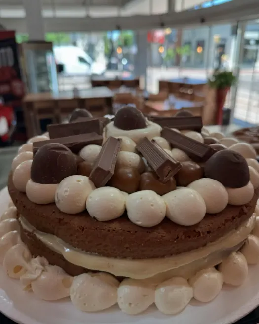 Torta de mousse de chocolate blanco con bombones, con las mesas del salón de fondo